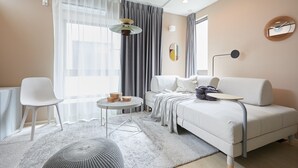 A modern living room with a white sofa, a round coffee table, a white chair, and a grey rug. - P OIN T Ikebukuro Designer's Villa (Tokyo)