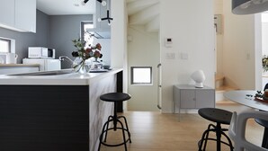 A modern kitchen with a central island, bar stools, a microwave, and a vase with flowers. - P OIN T Ikebukuro Designer's Villa (Tokyo)