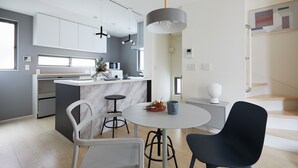 A modern kitchen with white cabinets, a marble island, and a dining area with a round table and chairs. - P OIN T Ikebukuro Designer's Villa (Tokyo)