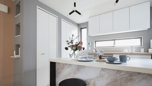 A modern kitchen with a marble countertop, white cabinets, and a black stool. - P OIN T Ikebukuro Designer's Villa (Tokyo)