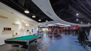 A modern indoor space with a pool table, exercise equipment, and flags on the walls. - Junyi Hotel (Shenzhen)