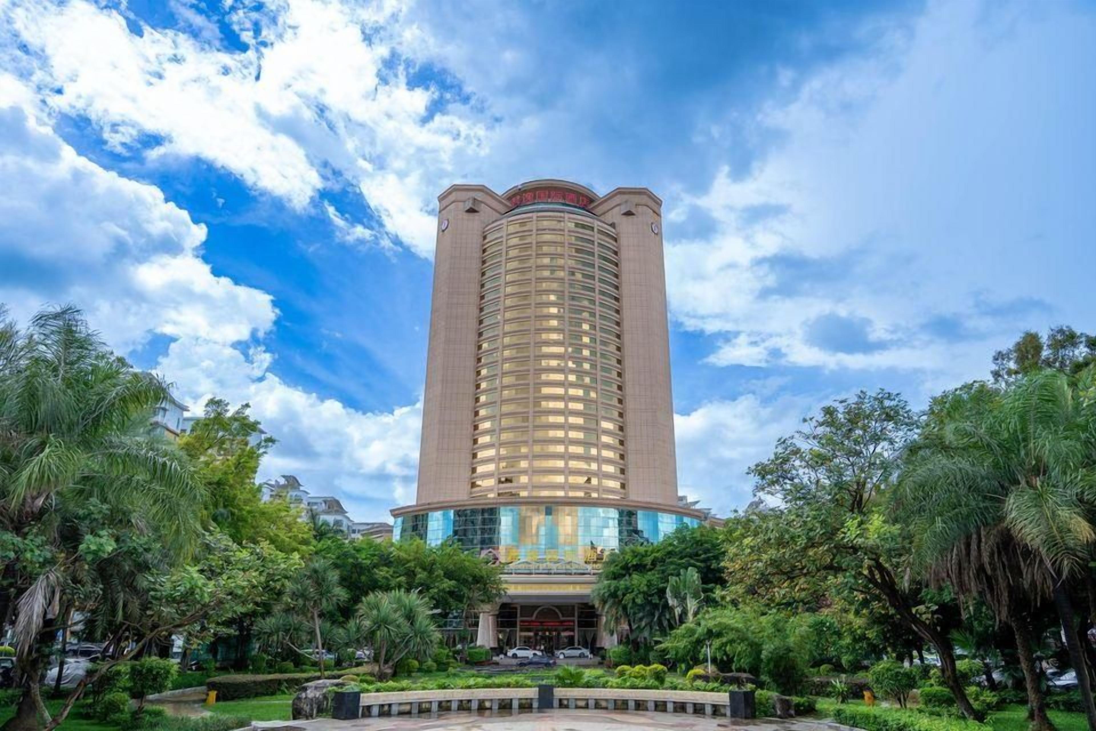 Um hotel alto e cilíndrico, com entrada central e fachada de vidro.