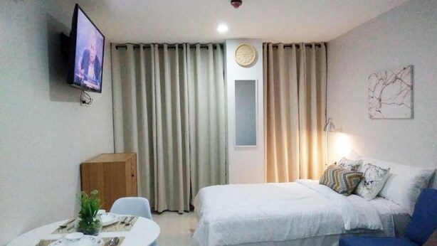 Une chambre d’hôtel avec un lit, une télévision, une table à manger avec des assiettes et un canapé bleu.