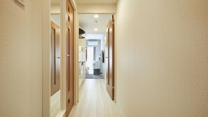 Un couloir avec des portes en bois, un plancher de couleur claire et un plafond doté d’un éclairage encastré.