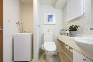 A compact bathroom with a toilet, bidet, and a sink.