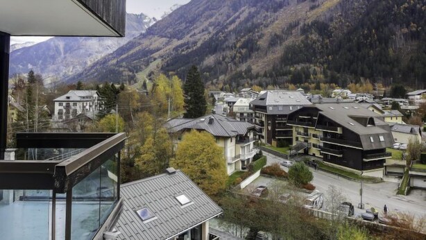 Un village de montagne aux bâtiments traditionnels, agrémenté d’une structure moderne dotée d’un balcon en verre.