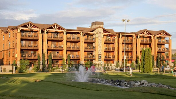 A multi-story hotel with balconies, a central fountain, and a well-maintained lawn. - Lake Chelan - Lake House (Chelan)