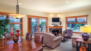 A spacious living room with a fireplace, comfortable seating, and large windows offering a view of the outdoors. - Lake Chelan - Lake House (Chelan)