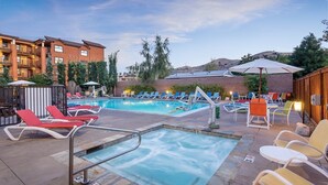 A pool area with lounge chairs and umbrellas, surrounded by buildings and trees. - Lake Chelan - Lake House (Chelan)