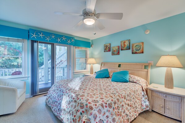 A bedroom with a large bed, a ceiling fan, and a view of the outside through a sliding glass door.