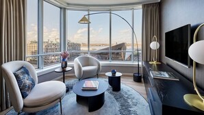A modern hotel room with a large window offering a city view, a flat-screen TV, and contemporary furniture. - Rotterdam Marriott Hotel (Rotterdam)