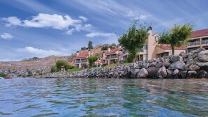 Un hotel frente al mar con aguas cristalinas, paredes de piedra y varios edificios con tejados rojos.