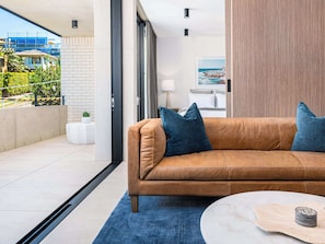 A modern living room with a leather sofa, a round coffee table, and a view of the outside.