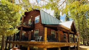 A log cabin with a balcony, surrounded by trees.