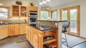 Une cuisine moderne avec des meubles en bois, un pare-feu en carreaux et un îlot central intégré doté d’un évier.