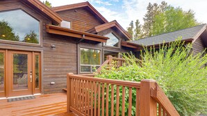 Une cabane en bois dotée de grandes fenêtres, d’une terrasse et offrant une vue sur les arbres.