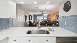 A modern kitchen with a central island, recessed ceiling lights, and a view to the living area. - SeaCrest 501AB - 3 BR Gulf Front  and Free Seasonal Beach Service (Fort Walton Beach)