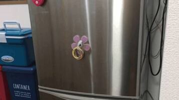 Een roestvrijstalen koelkast met een bloemmagneet in roze en paarse tinten op de deur.