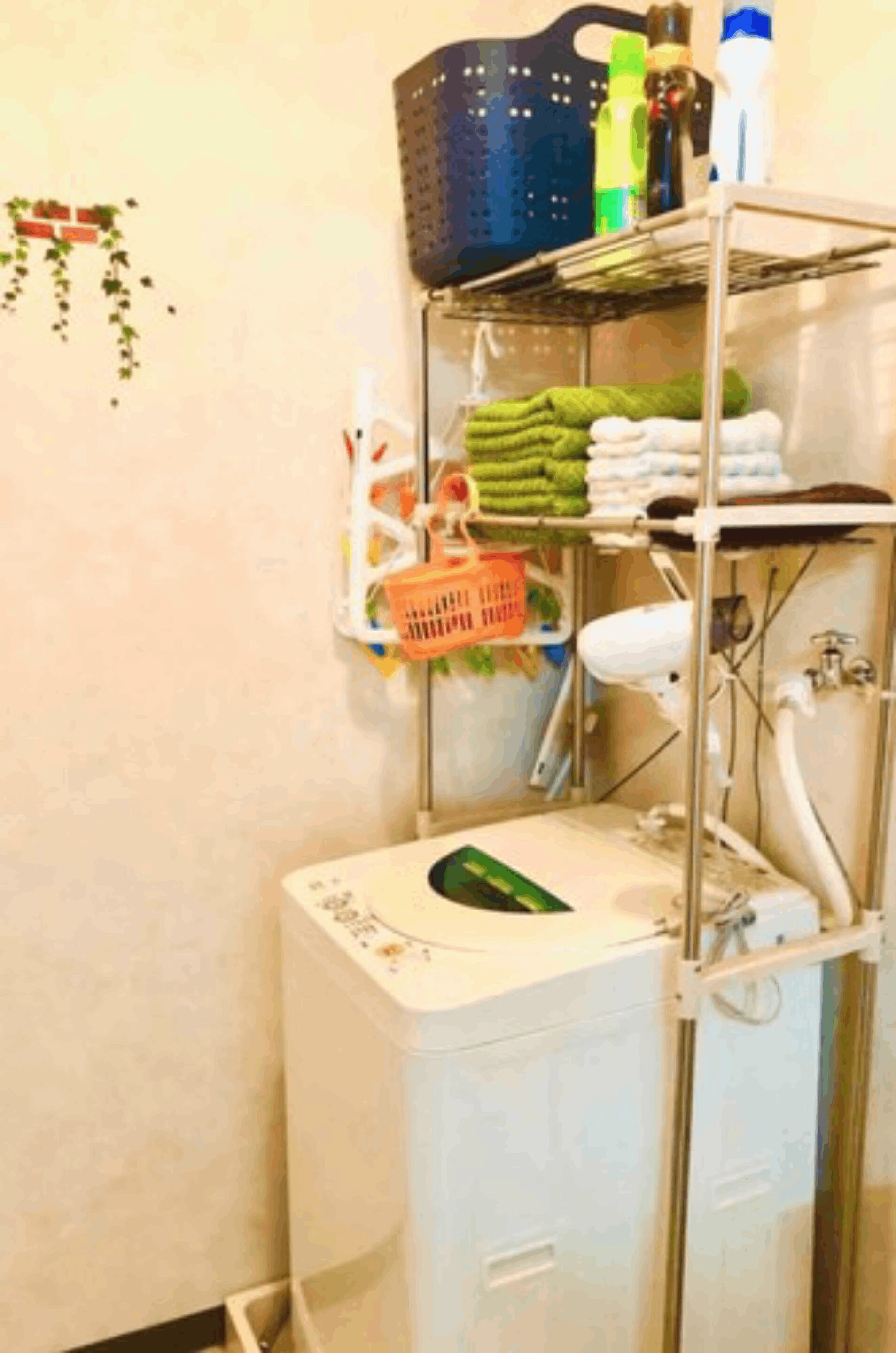 A compact bathroom with a washing machine, shelves with towels and toiletries, and a small sink.