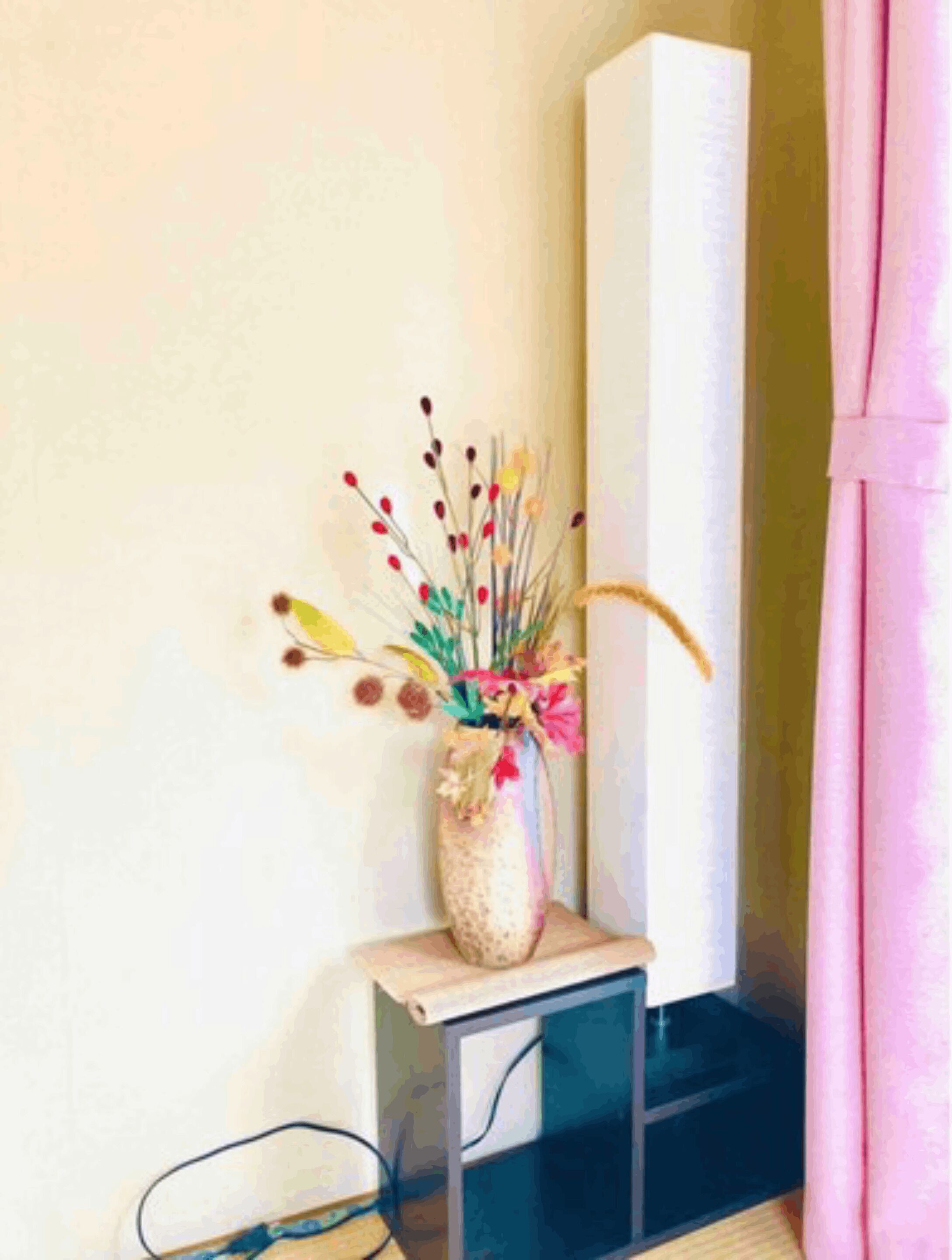 A corner of a room with a small table holding a vase with flowers.