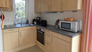 Una cucina con mobili in legno, un lavello in acciaio inox, un forno a microonde e un piano cottura.