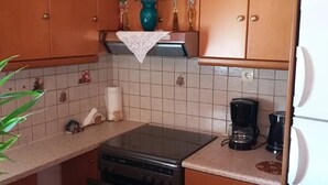 Een keuken met houten kastjes, een fornuis, een koffiezetapparaat en een koelkast.
