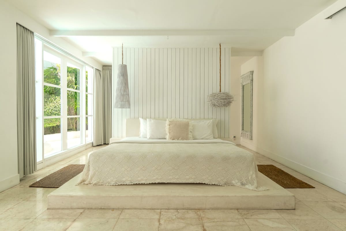 Een moderne slaapkamer met een groot bed, een hanglamp en uitzicht door het raam.