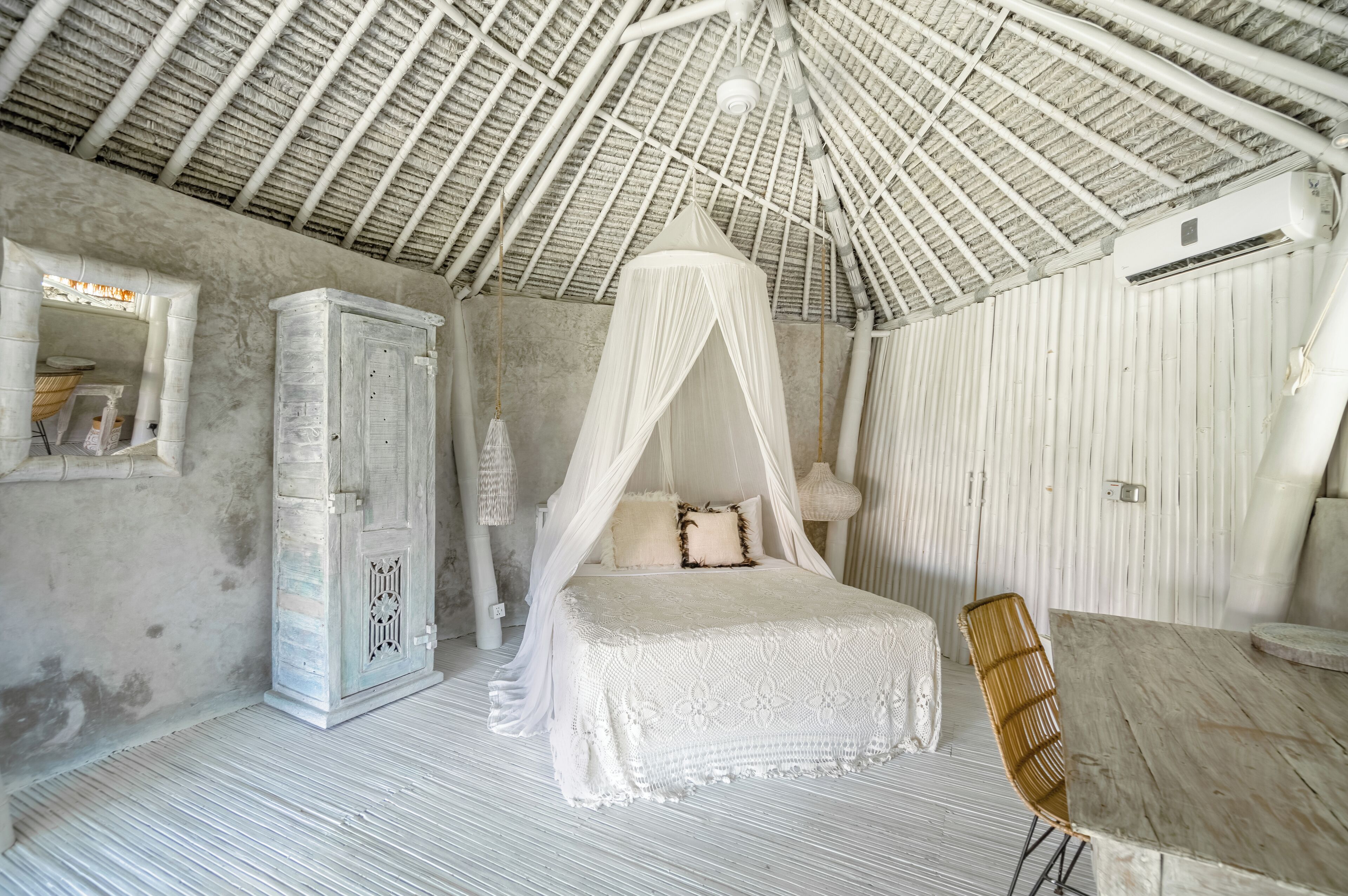 A bedroom with a canopy bed, a wardrobe, a table, and a chair.