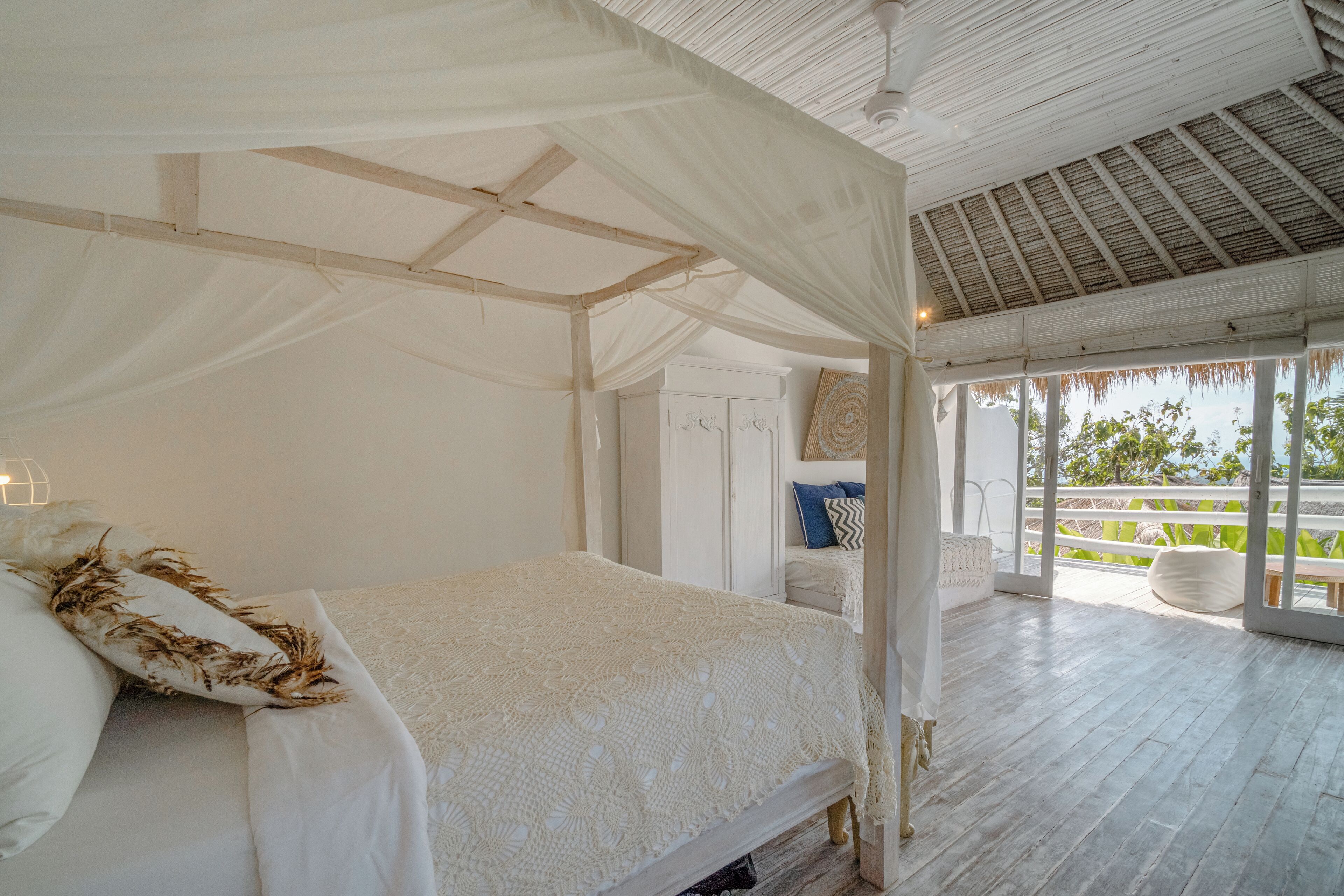 Un dormitorio amplio con una cama con dosel, suelo de madera y vistas al exterior.