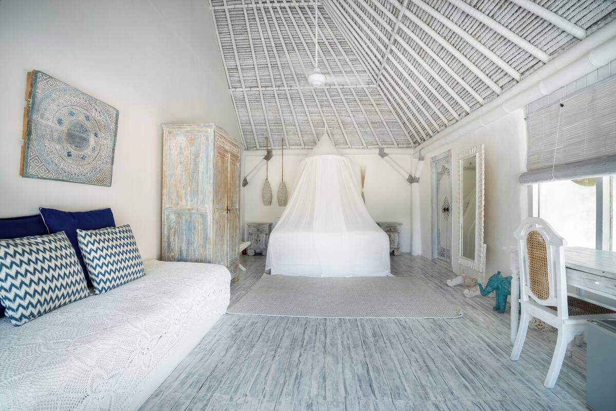 Een ruime slaapkamer met een groot bed, een hemelbed en een wit plafond.