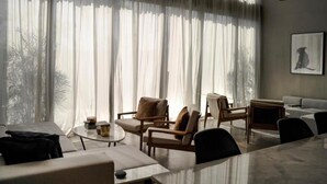 A modern living room with a large window, a sofa, a coffee table, and a dining table.