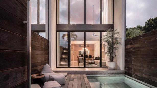 A modern outdoor living area with a pool, wooden deck, and seating.