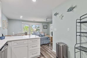 A modern kitchen with white cabinetry, a built-in island, and a dining area with a blue sofa.
