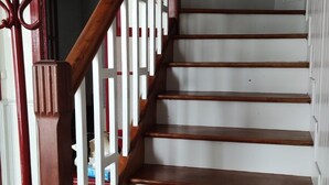 Una escalera de madera con barandillas blancas y un pasamanos rojo.