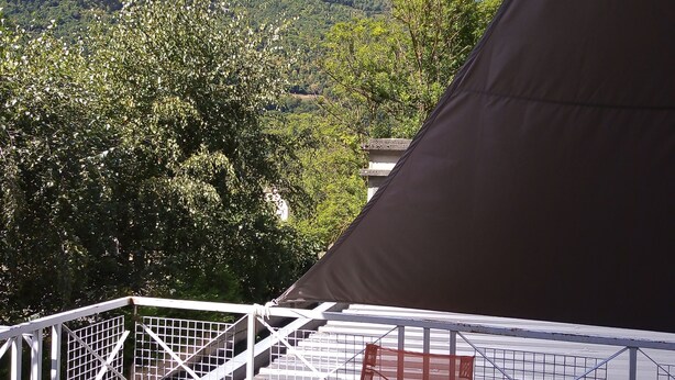 Un balcón con vista a una montaña, una tienda de campaña y una silla.