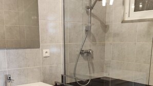 Un baño moderno con cabina de ducha de vidrio, un lavabo blanco y un espejo.