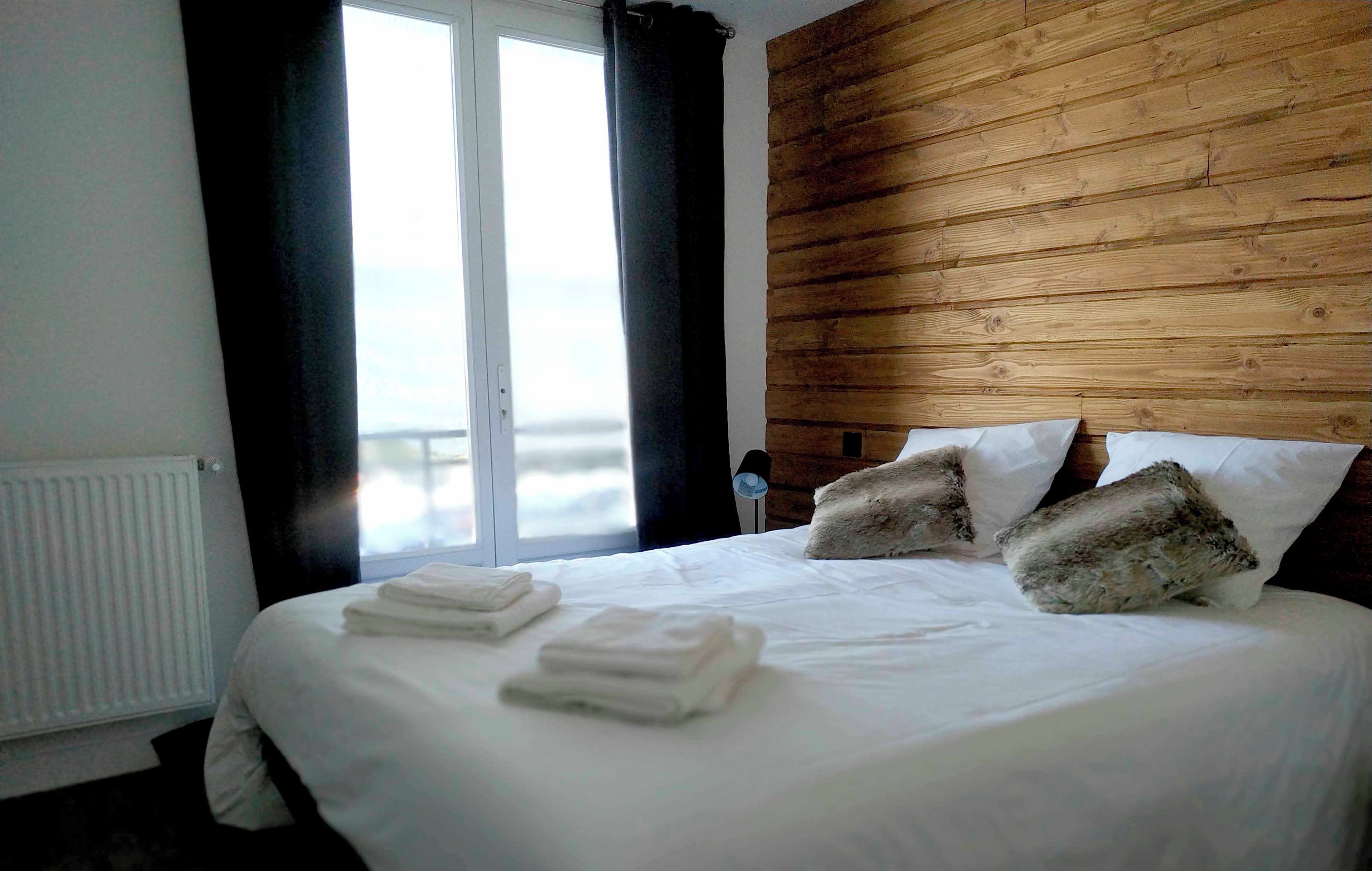 A bedroom with a large bed, white linens, and a wooden headboard.