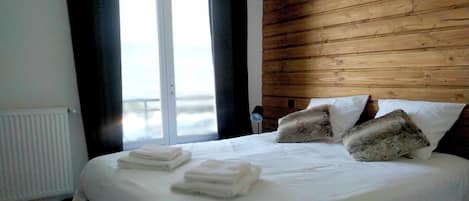Un dormitorio con una cama grande, ropa de cama blanca y un cabecero de madera.