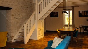 Un vaste espace de vie agrémenté d’un escalier en bois, d’une table à manger avec des chaises et d’un canapé bleu.