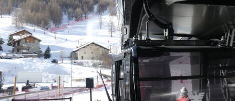 A ski lift cabin with a view of a snowy mountain and a lodge.