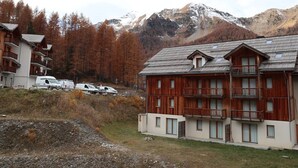 A mountain lodge with multiple wooden buildings, a parking area, and a view of snow-capped mountains.