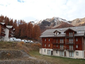 A mountain lodge with multiple wooden buildings, a parking area, and a view of snow-capped mountains.