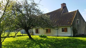 Una casa tradizionale con tetto in tegole, circondata da un prato curato e un grande albero.