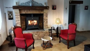 Un soggiorno accogliente con camino, due poltrone rosse rivestite in tessuto, un piccolo tavolino rotondo e una lampada decorativa.