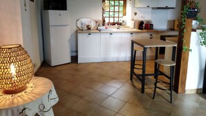 Una cucina con mobili bianchi, un tavolo di legno, un lampadario e una finestra con vista sul verde.