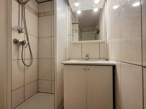 Ein Badezimmer mit Dusche, Waschbecken und Spiegel.