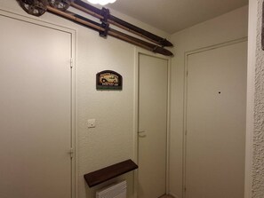 Ein Flur mit zwei geschlossenen Türen, einer Wandplakette und einem Holzregal.