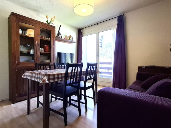 A dining area with a table, chairs, a cabinet, and a sofa.