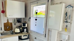 Une petite cuisine équipée d’un évier, d’une bouilloire, d’une machine à café et d’un petit réfrigérateur.