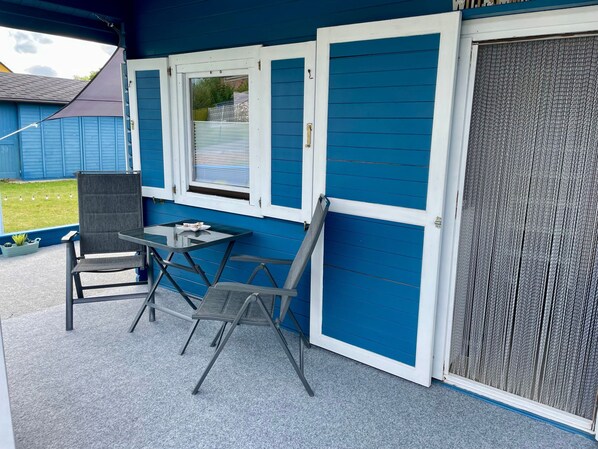Un patio techado con una mesa y sillas, una puerta corrediza y un ventanal.